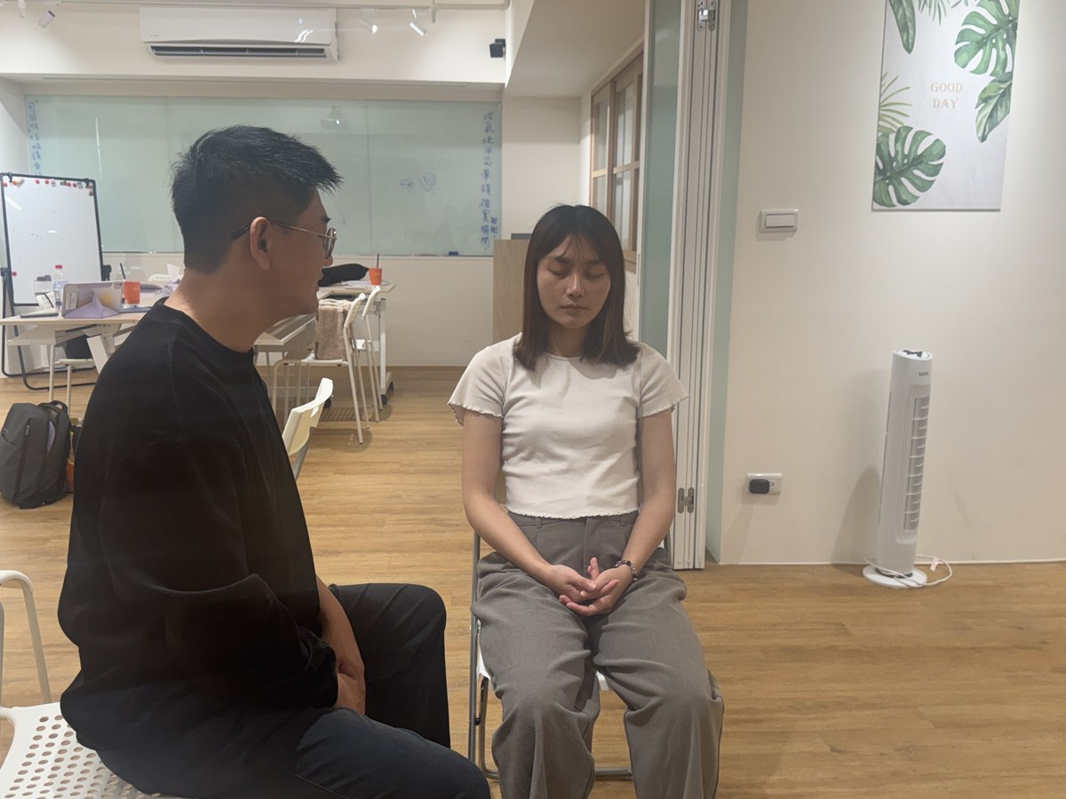 兩位學員面對面坐著練習，一位閉眼放鬆，另一位專注看著對方引導