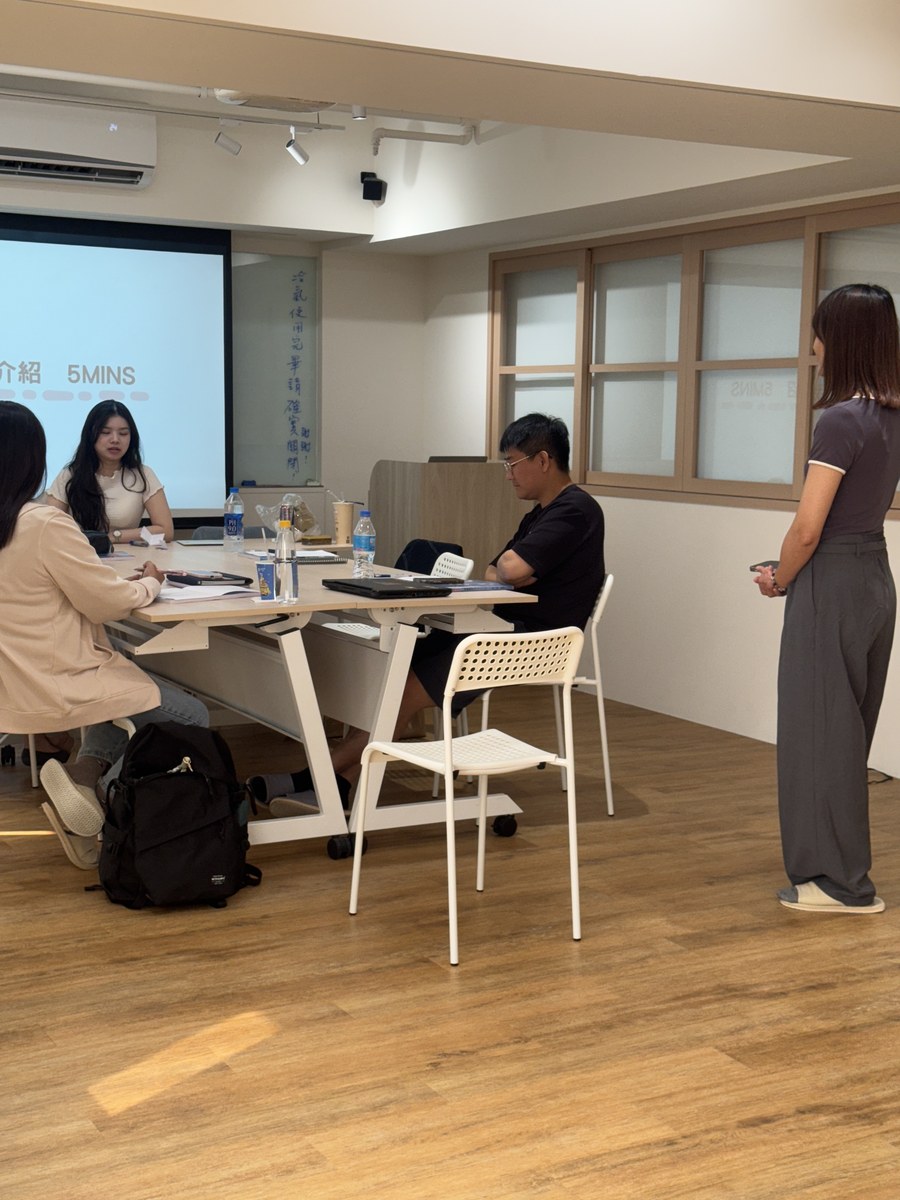 學員圍坐長桌進行自我介紹，一位站在旁邊聆聽